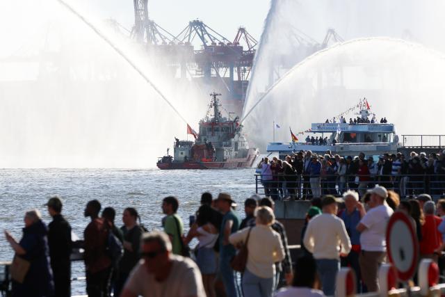 11 May 2025, Hamburg: Spectators at the port watch the departure parade at the end of the 836th Hamburg Port Birthday, led by the fireboat "Branddirektor Westphal" of the Hamburg Fire Department. Photo: Bodo Marks/dpa