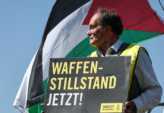 12 May 2025, Berlin: A participant in an Amnesty International protest against the Israeli war in the Gaza Strip holds a sign reading "Ceasefire now!" in front of the Federal Chancellery. The Israeli President visits Germany to mark the establishment of diplomatic relations between the Federal Republic of Germany and Israel 60 years ago. Photo: Hannes P. Albert/dpa