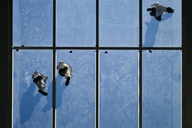 21 May 2025, Berlin: Workers replacing the seals on the Haus der Bundespressekonferenz stand on the glass roof. Photo: Sebastian Gollnow/dpa