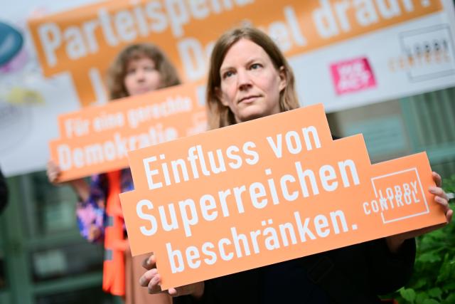 22 May 2025, Berlin: "Limit the influence of the super-rich" is written on a sign from the non-governmental organization Lobbycontrol before a hearing on a lawsuit against the Bundestag administration over two large donations to the Berlin CDU at the Berlin Administrative Court. The party of satirist and MEP Sonneborn wants the donations to be classified as illegal. Photo: Sebastian Christoph Gollnow/dpa