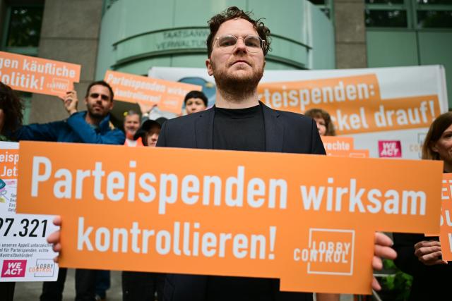 22 May 2025, Berlin: Aurel Eschmann, press spokesman for Lobbycontrol, holds a sign reading "Effective control of party donations!" before a hearing on a complaint against the Bundestag administration over two large donations to the Berlin CDU at the Berlin Administrative Court. The party of satirist and MEP Sonneborn wants the donations to be classified as illegal. Photo: Sebastian Christoph Gollnow/dpa
