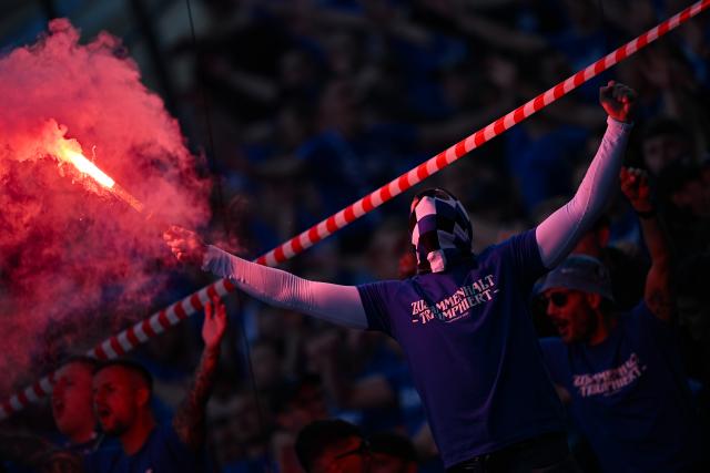 24 May 2025, Berlin: A Bielefeld fan sets of pyrotechnics in the stands before the start of the German DFB Cup final soccer match between Arminia Bielefeld and VfB Stuttgart at the Olympiastadion. Photo: Sebastian Gollnow/dpa