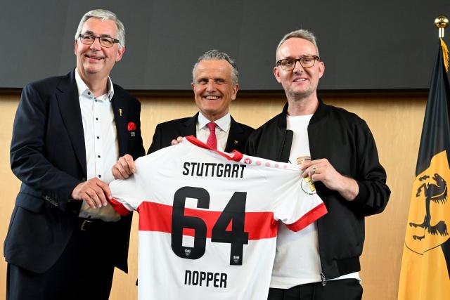 25 May 2025, Baden-Wuerttemberg, Stuttgart: Lord Mayor of Stuttgart Frank Nopper (C) receives a jersey with the number 64 from VfB President Dietmar Allgaier (L) and CEO of VfB Stuttgart Alexander Wehrle on his 64th birthday during the reception in the town hall after winning the DFB Cup final aginst Arminia Bielefeld. Photo: Uli Deck/dpa