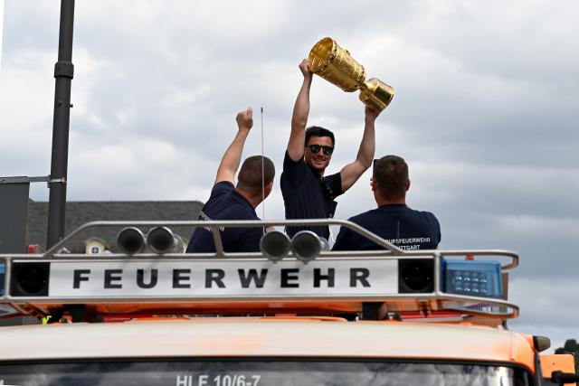 25 May 2025, Baden-Wuerttemberg, Stuttgart: Members of the Stuttgart fire department celebrate with the DFB Cup in a vehicle during the motorcade to Schlossplatz after winning the final aginst Arminia Bielefeld. Photo: Marijan Murat/dpa