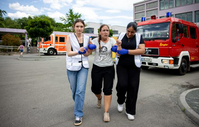 31 May 2025, Saarland, Saarbruecken: (L-R) Lilly Weinland and Cehaer Ahmad bring an actress portraying a slightly injured person to the assembly point. Photo: Laszlo Pinter/dpa