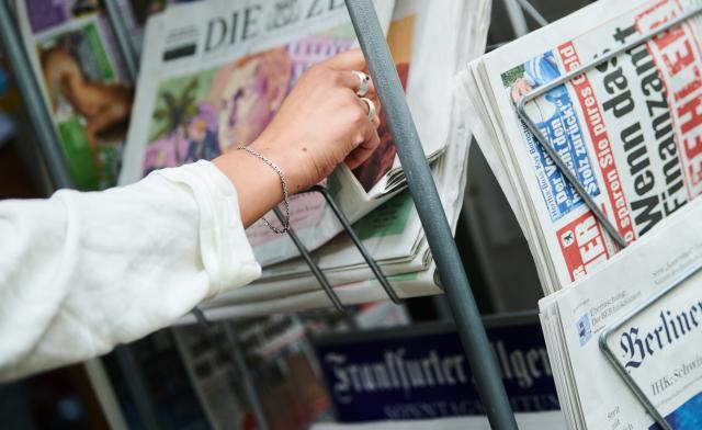 FILED - 26 July 2022, Berlin: A woman takes a weekly newspaper from a magazine rack in Berlin. A record number of people in Germany are choosing to avoid the news, citing emotional strain and a desire to protect their mental well-being, according to the Reuters Institute Digital News Report 2025. Photo: Annette Riedl/dpa
