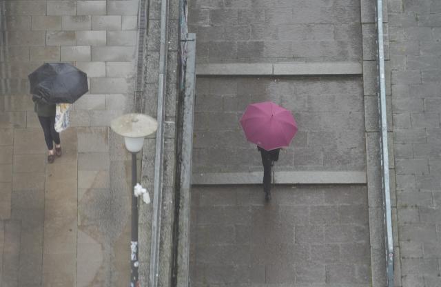 23 June 2025, Hamburg: Passers-by walk through the city center with umbrellas in the pouring rain. Photo: Marcus Brandt/dpa