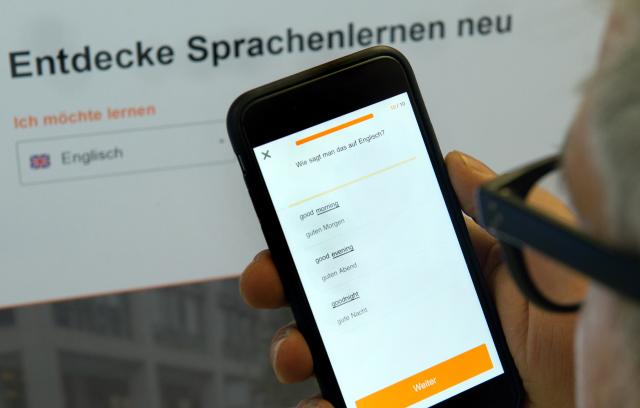 FILED - 02 February 2015, Berlin: ILLUSTRATION - A man holds up a smartphone displaying the foreign language learning app 'Babbel' in his office in Berlin. Photo: Arno Burgi/dpa-Zentralbild/dpa