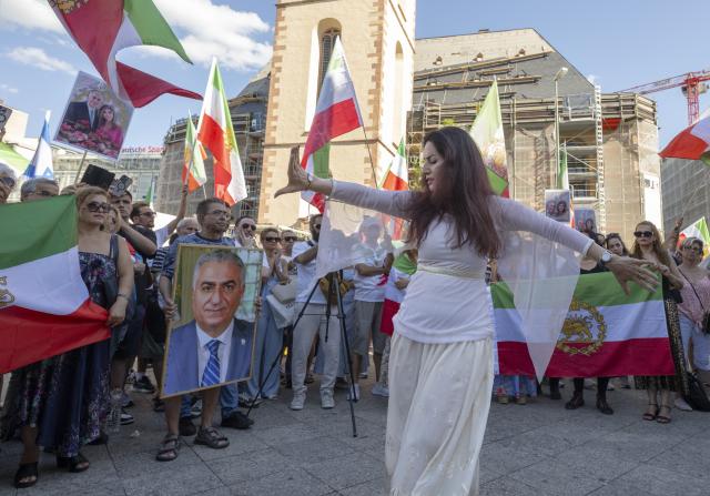 28 June 2025, Hesse, Frankfurt/Main: A woman dances while others hold a picture of Reza Pahlavi II, who lives in exile, during a protest against the Mullah regime in Iran at the Hauptwache in Frankfurt. Photo: Boris Roessler/dpa
