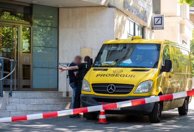 01 July 2025, Berlin: Police officers stand by an armored car on Kurfürstendamm. Unknown persons had previously started a robbery and exchanged gunfire with the police as they fled. Photo: Michael Kappeler/dpa