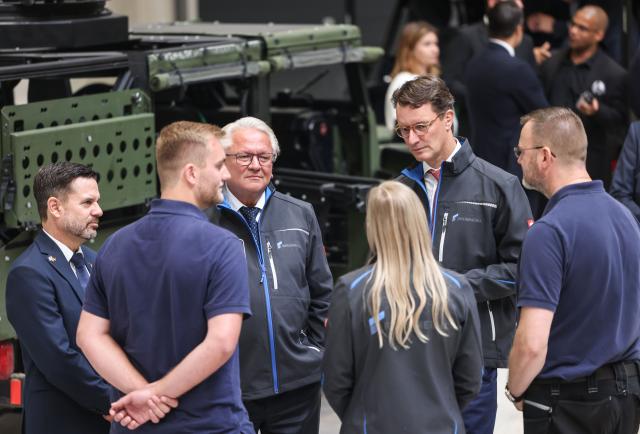 01 July 2025, North Rhine-Westphalia, Weeze: Armin Papperger (3-L), CEO of the Rheinmetall armaments group, and Hendrik Wüst (2-R), Minister President of North Rhine-Westphalia, talk to employees at the Rheinmetall Aviation Service GmbH plant in Weeze. Rheinmetall is building a factory for military aircraft construction on an area of around 60,000 square meters. Fuselage center sections for the F-35 fighter jet are to be manufactured there from summer 2025. Photo: Oliver Berg/dpa