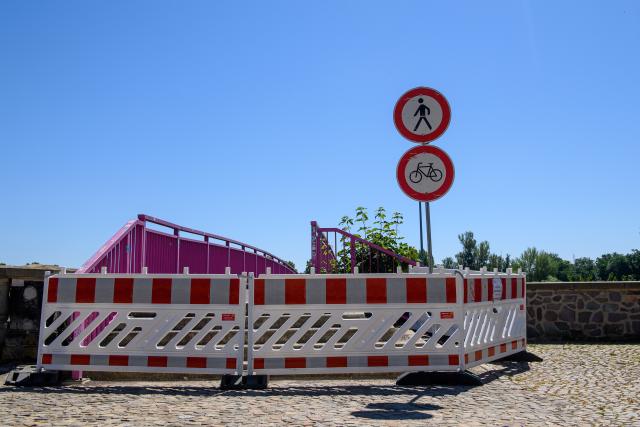 02 July 2025, Saxony-Anhalt, Magdeburg: "!!! Attention danger to life!!! - Demolition work" is written on a sign stuck to a barrier erected in front of a crossing to the banks of the Elbe. Due to considerable damage to the embankment wall, the city of Magdeburg has closed part of the Elbe riverbank promenade south of the Strombrücke bridge until further notice. Several cavities had been discovered in the structure in the affected section. The closure affects several hundred meters of the footpath and cycle path, which is an important traffic artery for many cyclists in Magdeburg. Photo: Klaus-Dietmar Gabbert/dpa