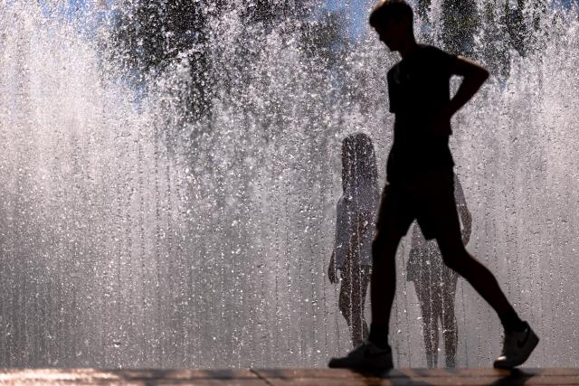 02 July 2025, Bavaria, Nuremberg: Young people walk through the water installation "Hexagonal Water Pavilion" by Danish artist Jeppe Hein in front of the Neues Museum. The installation in the form of a walk-in fountain is a popular way to cool off in summer temperatures. Photo: Daniel Karmann/dpa