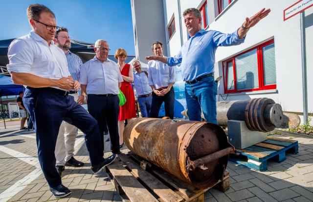02 July 2025, Mecklenburg-Western Pomerania, Rostock: Carsten Schneider (L), Germany's Environment Minister, and Till Backhaus (3rd L), Mecklenburg-Western Pomerania's Environment Minister, visit the Ocean Technology Campus in Rostock and are briefed on sea munition recovery by Eyk-Uwe Pap (R), using a 500-kg WWII bomb from the Baltic Sea as an example. Photo: Jens Büttner/dpa
