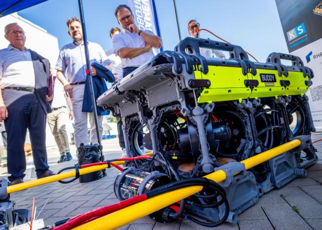 02 July 2025, Mecklenburg-Western Pomerania, Rostock: Carsten Schneider (C), Germany's Minister for the Environment, Climate Protection and Nature Conservation, visits the Ocean Technology Campus to learn about the use of diving robots in locating munitions in the Baltic Sea. The OTC presents itself as a potential site for a federal competence center for recovering munitions from the North and Baltic Seas. Photo: Jens Büttner/dpa