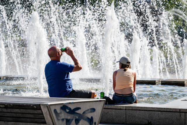 02 July 2025, Berlin: Two British tourists sit at Alexanderplatz in high temperatures. Photo: Fabian Sommer/dpa