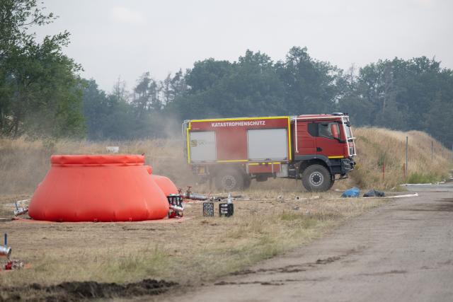 03 July 2025, Saxony, Zeithain: A fire department vehicle stands behind an extinguishing water tank at a forest and vegetation fire in the Gohrischheide in the district of Meißen near the Saxon town of Zeithain. The forest fire in the Gohrischheide, a former military training area in Saxony, has spread considerably. Photo: Sebastian Kahnert/dpa