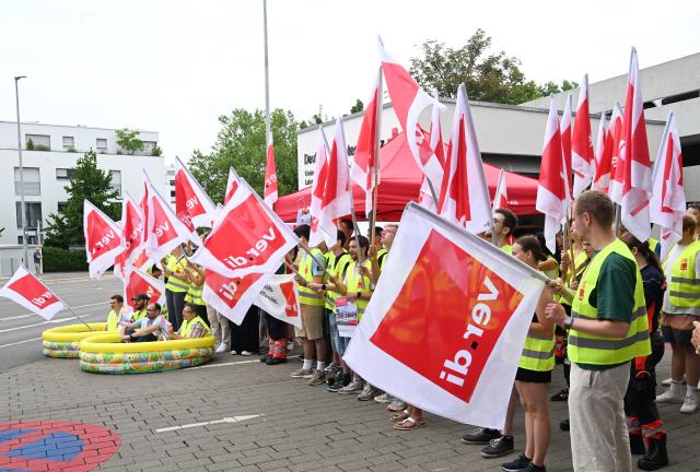 03 July 2025, Baden-Württemberg, Reutlingen: Employees of the German Red Cross (DRK) stand and sit in paddling pools during a warning strike with union flags in front of a rescue station. The union is calling for work stoppages in the ongoing nationwide collective bargaining round with the German Red Cross. Photo: Bernd Weißbrod/dpa