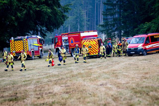 03 July 2025, Thuringia, Reichmannsdorf: Emergency services stand at the edge of the forest on the Saalfelder Höhe in Thuringia. A disaster alert has been issued due to the forest fire in the district of Saalfeld-Rudolstadt. The extinguishing work continues. Photo: Jacob Schröter/dpa