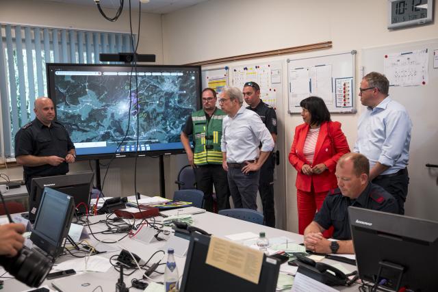 05 July 2025, Thuringia, Reichmannsdorf: Mario Voigt (R), Thuringia's Minister President, is briefed at the operations center by Georg Maier (C), Thuringia's Minister of the Interior, as Christian Patze (L), district fire inspector for the Saalfeld-Rudolstadt district, reports on the current situation at the forest fire on the Saalfelder Hoehe. Photo: Daniel Vogl/dpa