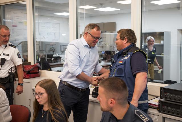 05 July 2025, Thuringia, Reichmannsdorf: Mario Voigt (C), Thuringia's Minister President, thanks emergency services at the operations center as he is briefed on the forest fire on the Saalfelder Hoehe. Photo: Daniel Vogl/dpa