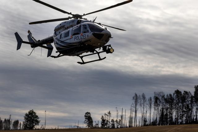 06 July 2025, Thuringia, Reichmannsdorf: A helicopter with a thermal imaging camera searches for hidden pockets of embers at the forest fire on the Saalfelder Hoehe. Photo: Michael Reichel/dpa