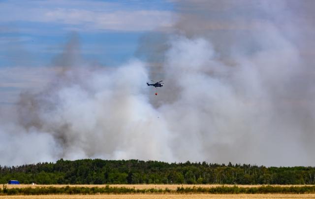 06 July 2025, Saxony, Jacobsthal: A federal police fire-fighting helicopter is deployed in the Gohrischheide forest fire. The forest area between Saxony and Brandenburg has been burning for several days. Photo: Robert Michael/dpa