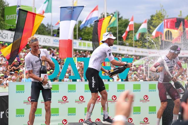 06 July 2025, Bavaria, Roth: (L-R) Second-placed German triathlete Jonas Schomburg, the winner French triathlete Sam Laidlow and third-placed German triathlete Jan Stratmann celebrate at the award ceremony after the Triathlon Challenge Ironman (3.86 km swim, 180 km bike, 42.195 km run). Photo: Daniel Karmann/dpa