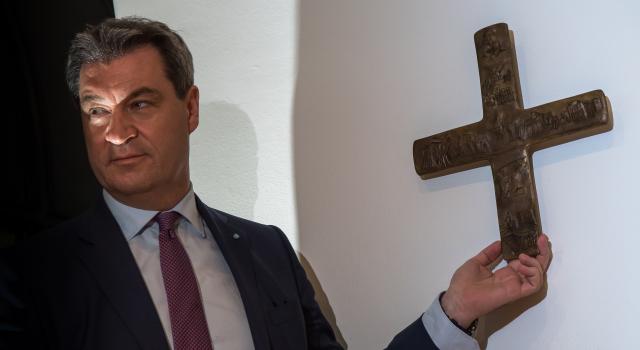 FILED - 24 April 2018, Bayern, München: Bavarian Minister President Markus Soeder hangs a cross in the entrance area of the Bavarian State Chancellery. A German court ruled on Wednesday that a cross displayed in the entrance to a state school in the southern state of Bavaria violates pupils' freedom of religion. Photo: Peter Kneffel/dpa