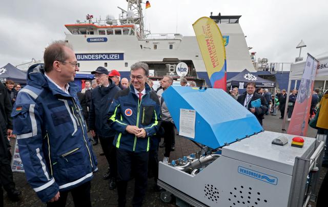 12 July 2025, Mecklenburg-Western Pomerania, Rostock: Alexander Dobrindt (L-R), Federal Minister of the Interior, Christian Pegel, Minister of the Interior of Mecklenburg-Western Pomerania, and Ralph Tiesler, President of the Federal Office of Civil Protection and Disaster Assistance, on a tour of the nationwide Civil Protection Day in the Hanseatic city's harbor. Photo: Bernd Wüstneck/dpa