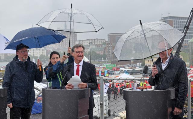 12 July 2025, Mecklenburg-Western Pomerania, Rostock: Christian Pegel (L-R), Minister of the Interior of Mecklenburg-Western Pomerania, Ralph Tiesler, President of the Federal Office of Civil Protection and Disaster Assistance, and Alexander Dobrindt, German Minister of the Interior, under umbrellas at the opening press conference of the nationwide Civil Protection Day in the Hanseatic city's harbor. Photo: Bernd Wüstneck/dpa