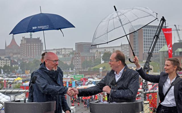 12 July 2025, Mecklenburg-Western Pomerania, Rostock: Christian Pegel (L-R), Interior Minister of Mecklenburg-Western Pomerania, and Alexander Dobrindt, German Minister of the Interior, under umbrellas at the opening press conference of the nationwide Civil Protection Day in the Hanseatic city's harbor. Photo: Bernd Wüstneck/dpa
