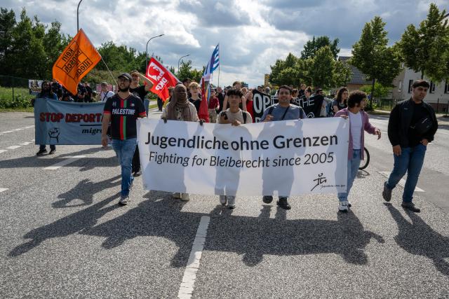 13 July 2025, Brandenburg, Schoenefeld: Participants in a demonstration against the planned deportation center at BER Airport carry a banner reading "Young People Without Borders. Fighting for the Right to Stay Since 2005." Photo: Soeren Stache/dpa