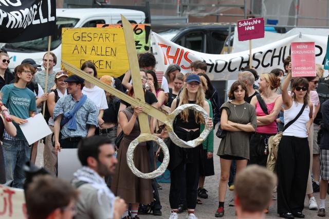 15 July 2025, Hesse, Wiesbaden: Participants in a rally against the black-red austerity plans for universities in Hesse stand on the Schloßplatz in front of the town hall. Photo: Jörg Halisch/dpa