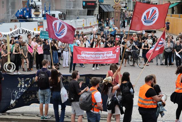 15 July 2025, Hesse, Wiesbaden: Participants in a rally against the black-red austerity plans for universities in Hesse stand on the Schloßplatz in front of the town hall. Photo: Jörg Halisch/dpa
