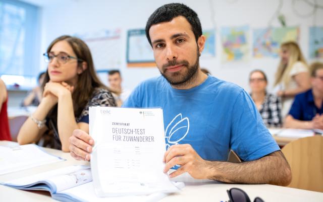 FILED - 04 June 2019, Bavaria, Munich: Serkan Beyde from Turkey is pleased about a certificate "German test for immigrants" which he received for his successful participation in an integration course for immigrants of the Federal Office for Migration (BAMF). Immigrants in Germany earn significantly less on average than native Germans, according to research published on Thursday. Photo: Sven Hoppe/dpa