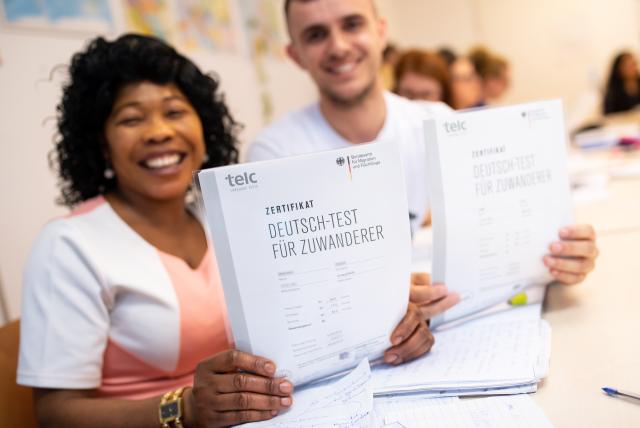 FILED - 04 June 2019, Bavaria, Munich: Angela Nwaubani from Nigeria and Enver Latifi from Kosovo are happy about their certificates "Deutsch-Test für Zuwanderer" (German test for immigrants) which they received for their successful participation in an integration course for immigrants of the Federal Office for Migration (BAMF). Immigrants in Germany earn significantly less on average than native Germans, according to research published on Thursday. Photo: Sven Hoppe/dpa