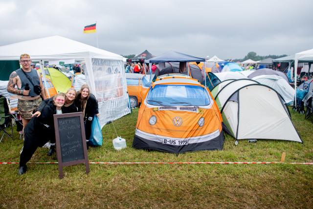 17 July 2025, Lower Saxony, Nordholz: Festival-goers stand next to a tent shaped like a Volkswagen T2 van at the Deichbrand Festival campsite. The open-air festival, attended by around 60,000 visitors, takes place from July 17 to 20. Photo: Hauke-Christian Dittrich/dpa - ATTENTION: editorial use only in connection with the latest coverage and only if the credit mentioned above is referenced in full