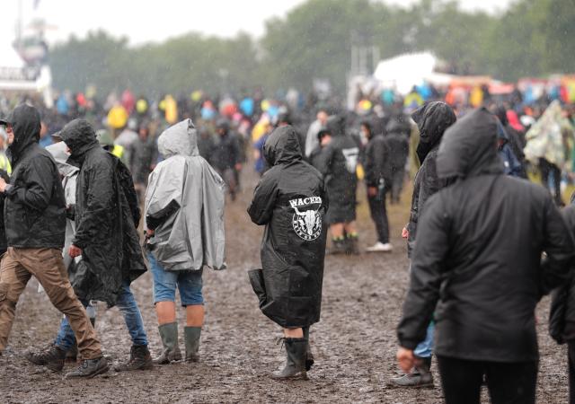 30 July 2025, Schleswig-Holstein, Wacken: Metal fans walk through the mud at the Wacken Open Air (WOA) heavy metal festival. Photo: Marcus Brandt/dpa