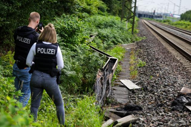 31 July 2025, North Rhine-Westphalia, Duesseldorf: Police officers from the forensics department check a section of track in Duesseldorf after a fire was set in a cable tunnel next to the railroad line, affecting six cables. Photo: Christoph Reichwein/dpa