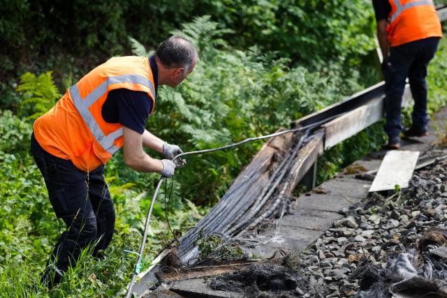 31 July 2025, North Rhine-Westphalia, Duesseldorf: Deutsche Bahn employees work on a section of track in Duesseldorf after a fire was set in a cable tunnel next to the railroad line, affecting six cables. Photo: Christoph Reichwein/dpa