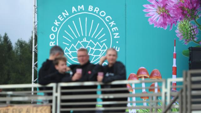 31 July 2025, Saxony-Anhalt, Elend: Visitors stand in front of the stage with the "Rocken am Brocken" music festival logo. Photo: Matthias Bein/dpa