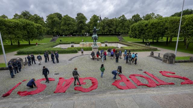 04 August 2025, Bavaria, Munich: Young people holding signs in front of the Bavarian State Chancellery take part in a Fridays for Future protest action against the planned drilling for natural gas in the Bavarian village of Reichling and have placed the words "Stop Gas!" made of red fabric on the ground in front of the grand staircase. Photo: Peter Kneffel/dpa