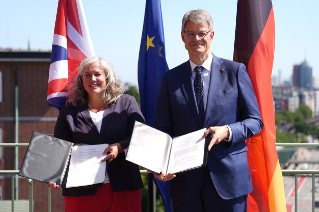 13 August 2025, Hamburg: German Minister for Transport Patrick Schnieder (R) and UK Transport Minister Heidi Alexander hold up the joint declaration of intent for a future direct cross-border long-distance passenger rail link between Germany and the UK on the roof terrace of the Federal Maritime and Hydrographic Agency. Photo: Marcus Brandt/dpa