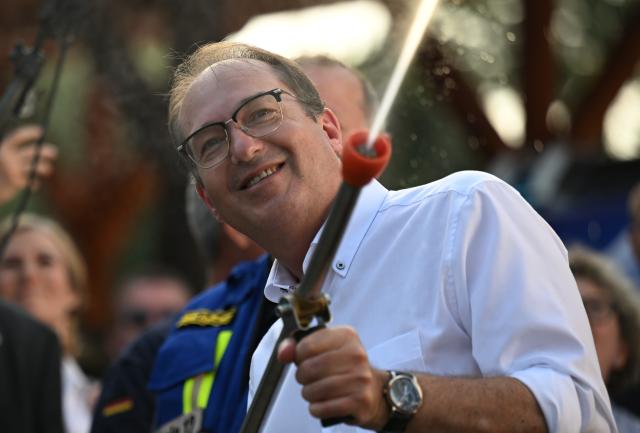 14 August 2025, Saxony-Anhalt, Quedlinburg: Alexander Dobrindt, German Minister of the Interior,uses a fire extinguisher during his visit to the THW Quedlinburg branch. The visit is part of the Federal Minister of the Interior's summer trip. Photo: Hendrik Schmidt/dpa