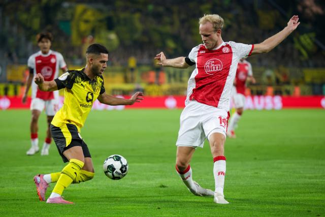 18 August 2025, North Rhine-Westphalia, Essen: Borussia Dortmund's Yan Couto (L) and Essen's Lucas Brumme battle for the ball during the German DFB Cup 1st round soccer match between Rot-Weiss Essen and Borussia Dortmund at Stadion an der Hafenstrasse. Photo: Christoph Reichwein/dpa - WICHTIGER HINWEIS: Gemäß den Vorgaben der DFL Deutsche Fußball Liga bzw. des DFB Deutscher Fußball-Bund ist es untersagt, in dem Stadion und/oder vom Spiel angefertigte Fotoaufnahmen in Form von Sequenzbildern und/oder videoähnlichen Fotostrecken zu verwerten bzw. verwerten zu lassen.