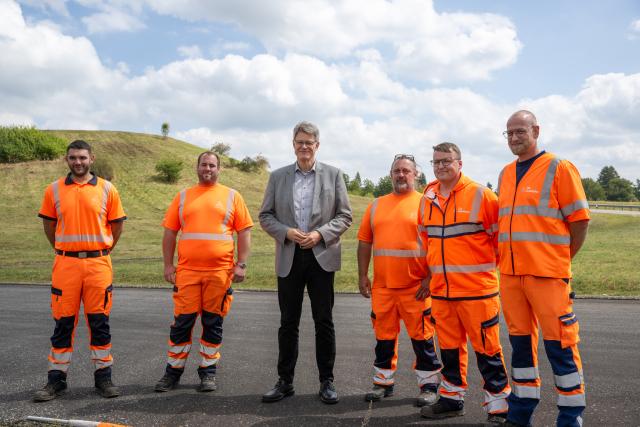 21 August 2025, Rhineland-Palatinate, Kelberg: German Transport Minister Patrick Schnieder (R) poses for a photo surrounded by employees of the Wittlich autobahn maintenance depot, who are responsible for this section at the Kelberg junction of the A1 autobahn. Photo: Harald Tittel/dpa