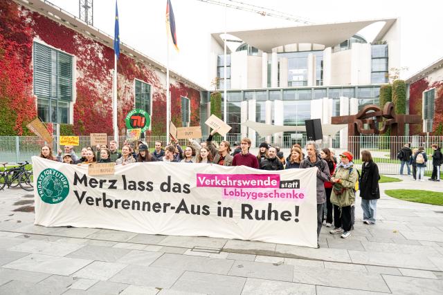 09 October 2025, Berlin: Activists hold a placard reading "Merz leave the end of the combustion engine alone!" in front of the Chancellery during a protest at the government's "car summit" organized by Fridays for Future. Photo: Fabian Sommer/dpa