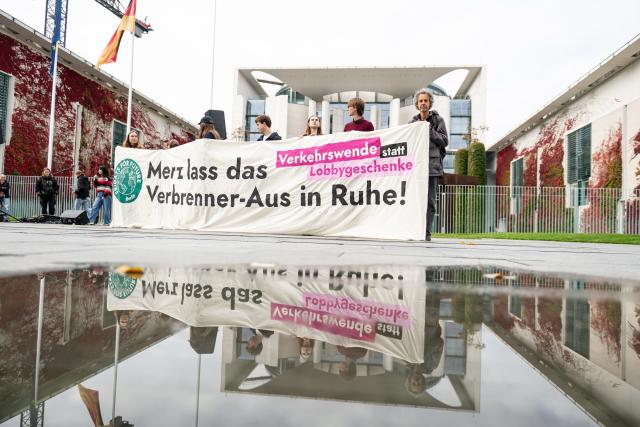 09 October 2025, Berlin: Activists hold a placard reading "Merz leave the end of the combustion engine alone!" in front of the Chancellery during a protest at the government's "car summit" organized by Fridays for Future. Photo: Fabian Sommer/dpa