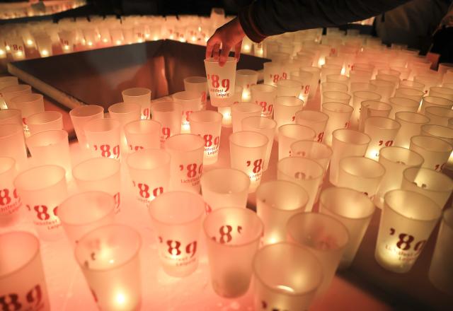 09 October 2025, Saxony, Leipzig: A visitor to the Festival of Lights places her candle in the big '89 in Leipzig city center. Every year on October 9, the people of Leipzig commemorate the Monday demonstrations in the fall of 1989, which led to the fall of the SED regime and paved the way for German reunification. Photo: Jan Woitas/dpa